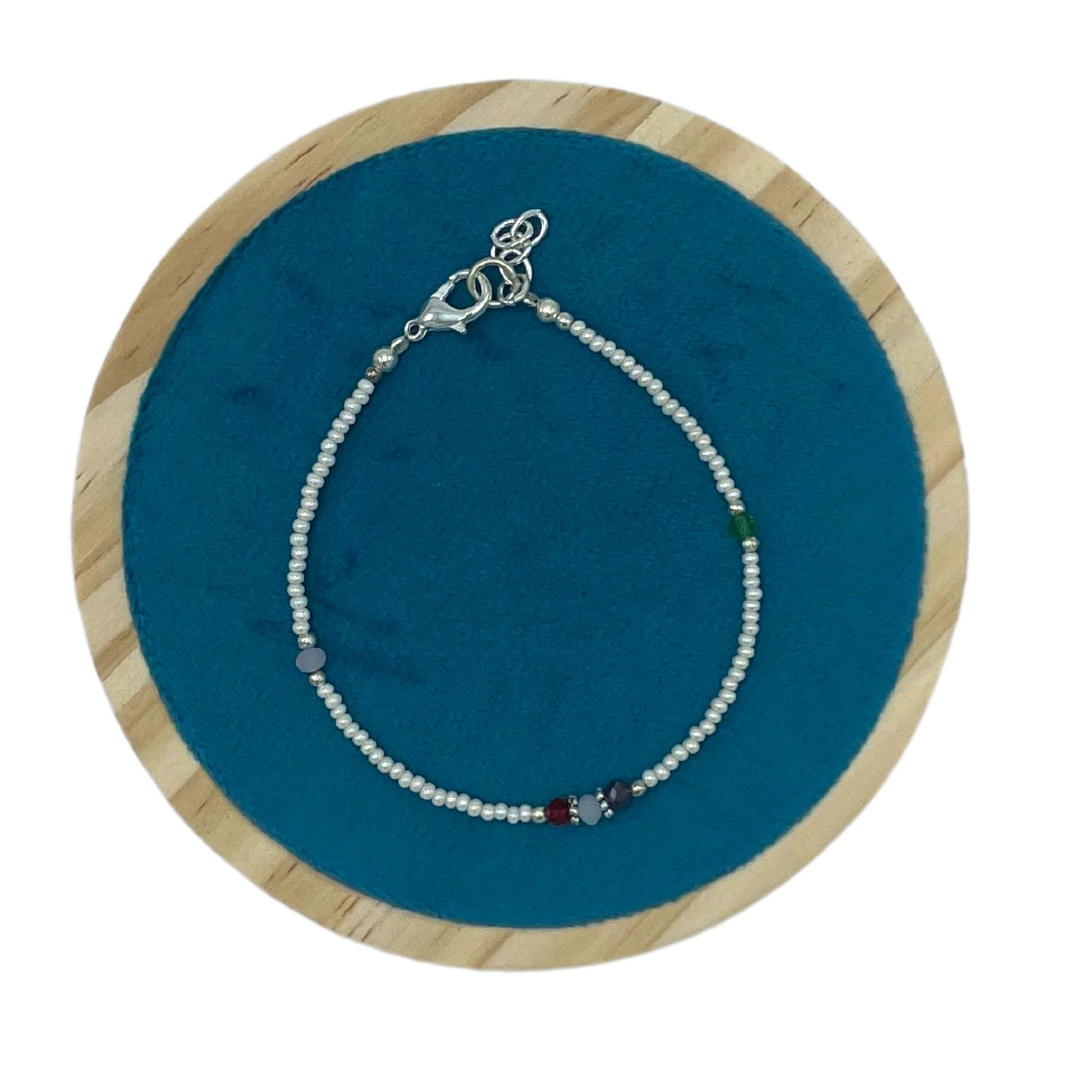 Pulsera de cuentas multicolores con detalles en plata, estilo bohemio, sobre fondo azul.