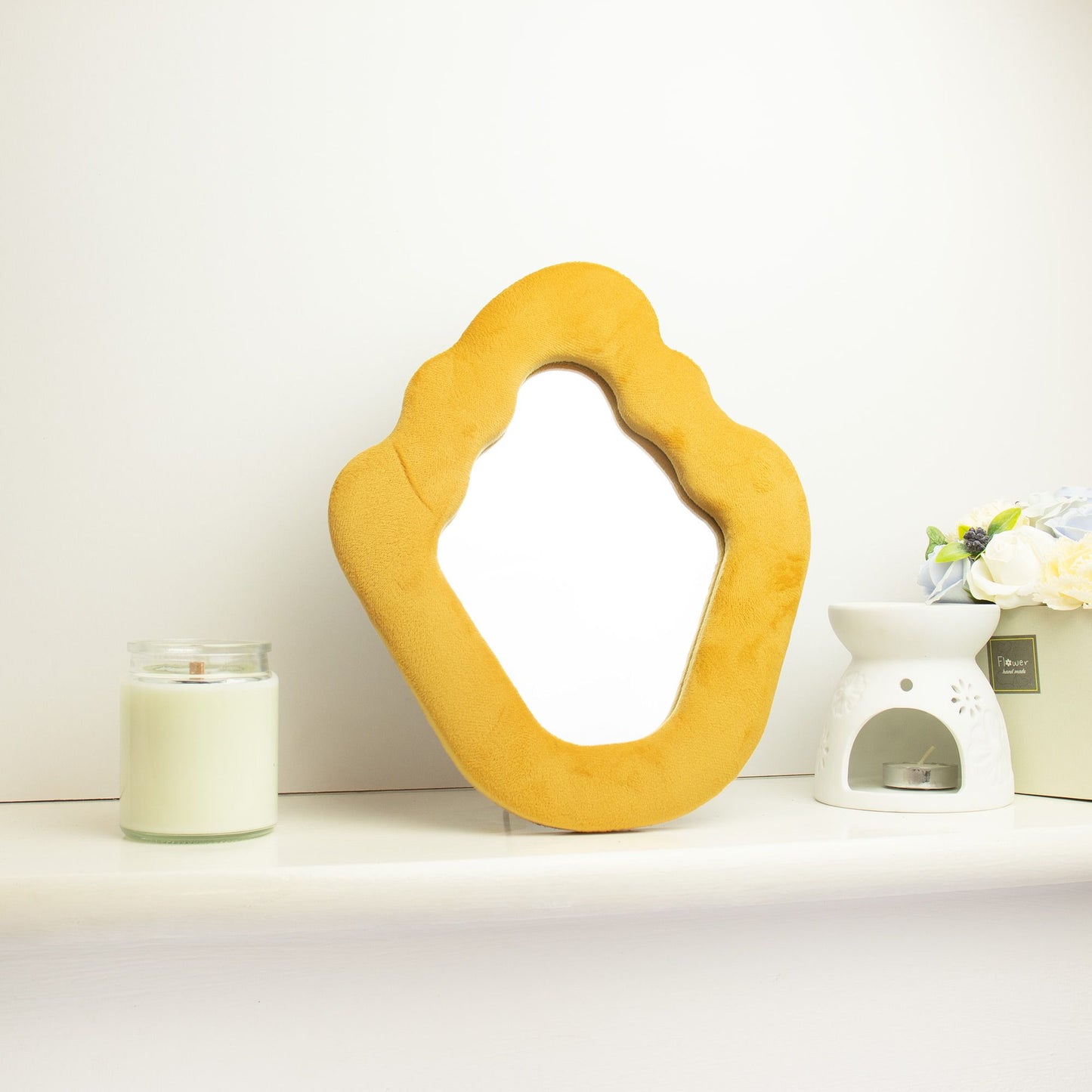 Espejo de pared de terciopelo amarillo en forma orgánica, ideal para decoración moderna y luminosa.
