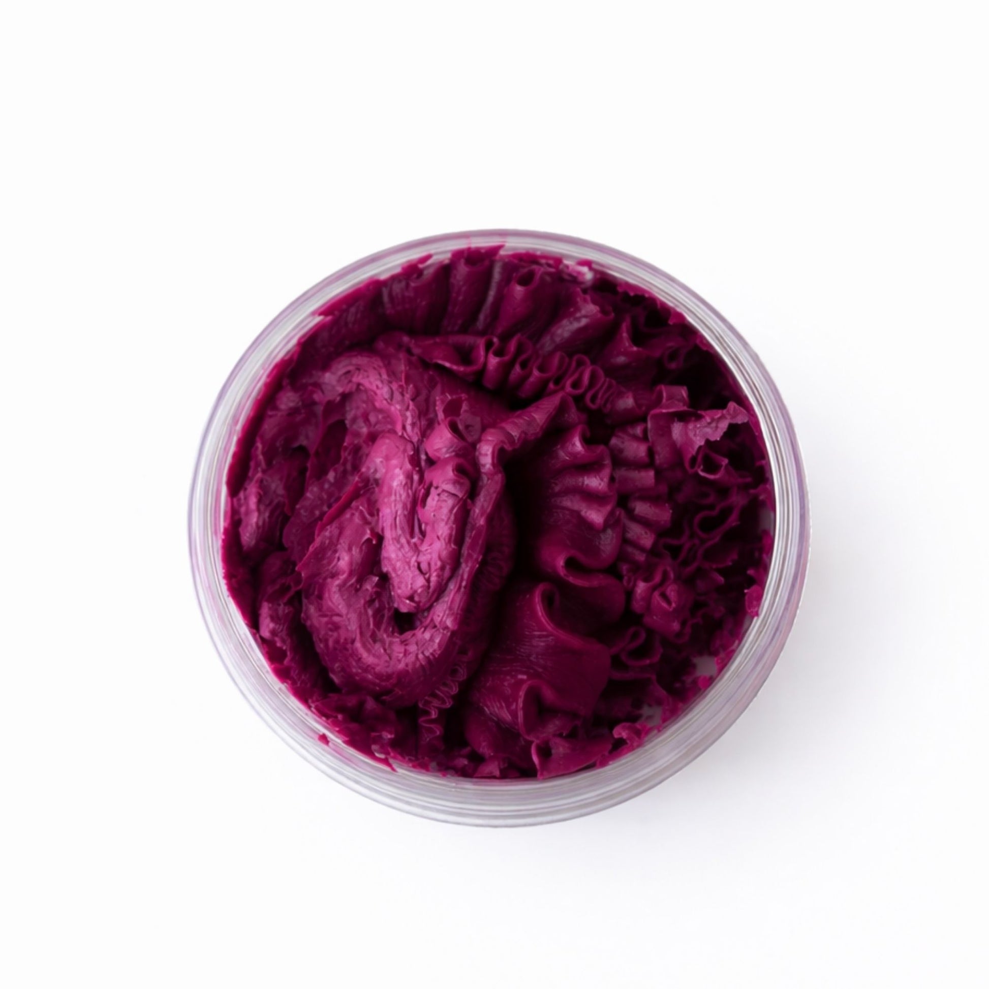 Crema de color púrpura en tarro transparente, con textura suave y rizada, ideal para tratamientos de belleza.
