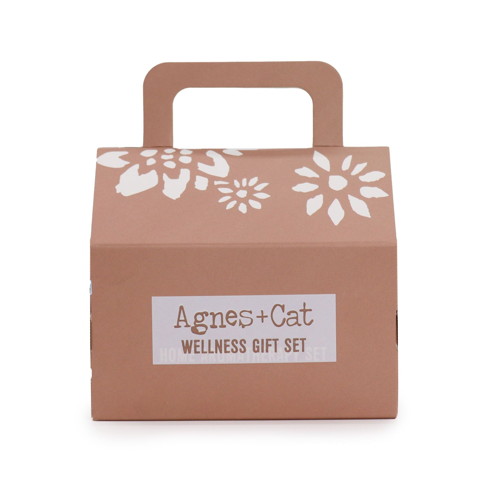 Caja de regalo color terracota con asa, flores blancas impresas y etiqueta con el logo Agnes + Cat Wellness Gift Set.