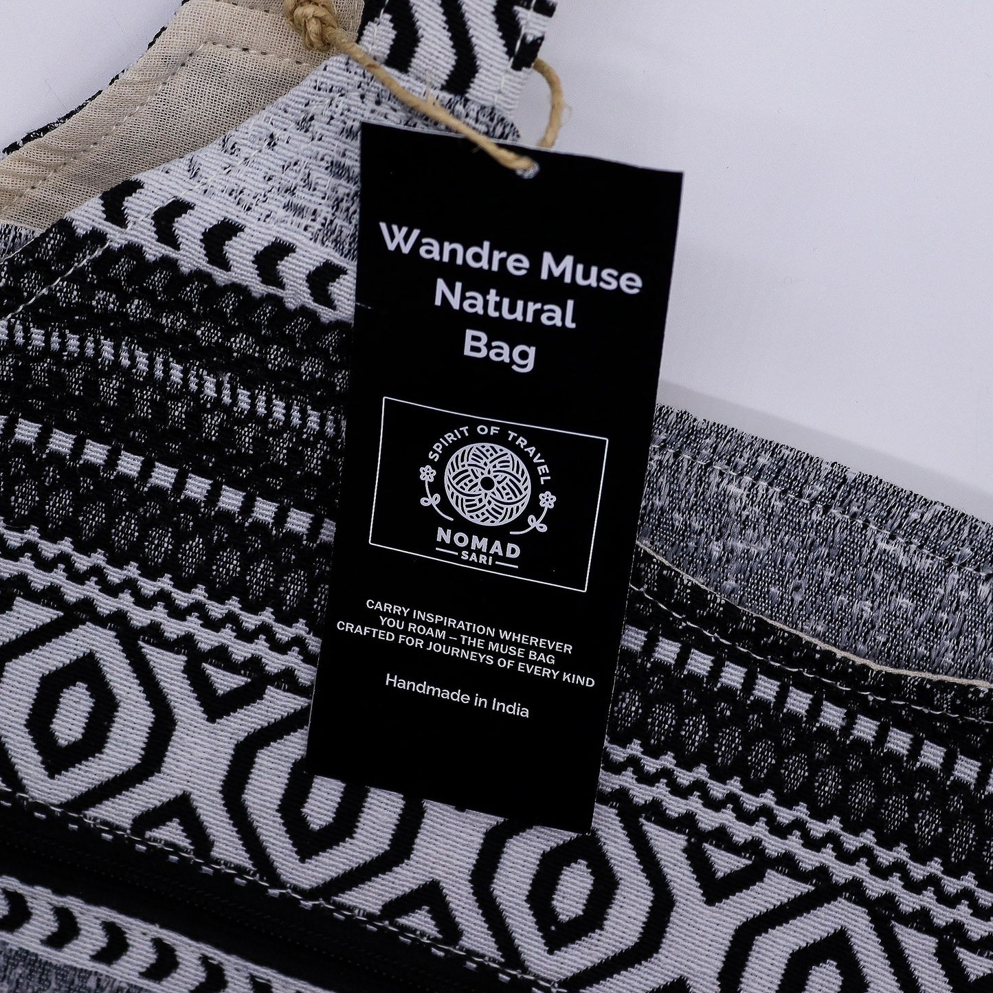 Bolso artesanal Wandre Muse, negro y blanco, con diseño geométrico y etiqueta de inspiración nómada, hecho en India.