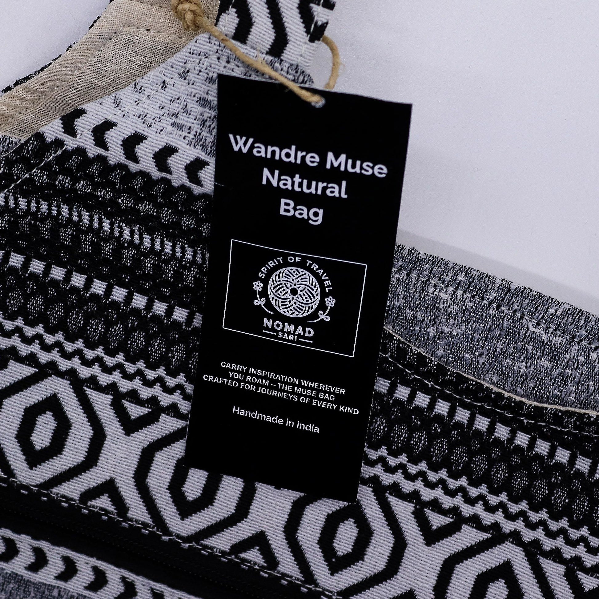 Bolso artesanal Wandre Muse, negro y blanco, con diseño geométrico y etiqueta de inspiración nómada, hecho en India.