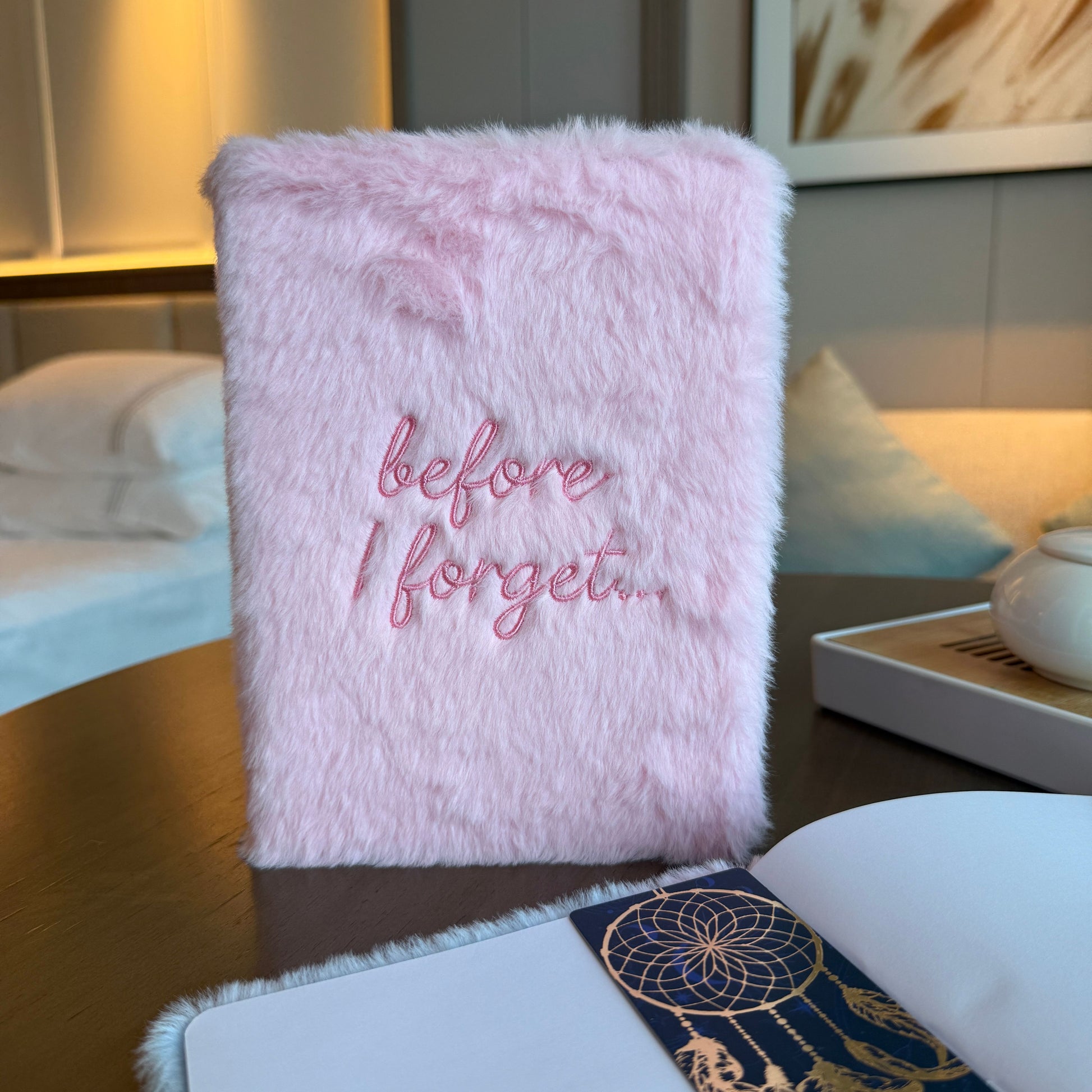 Cuaderno de peluche rosa con bordado "before I forget..." en estilo moderno y suave.