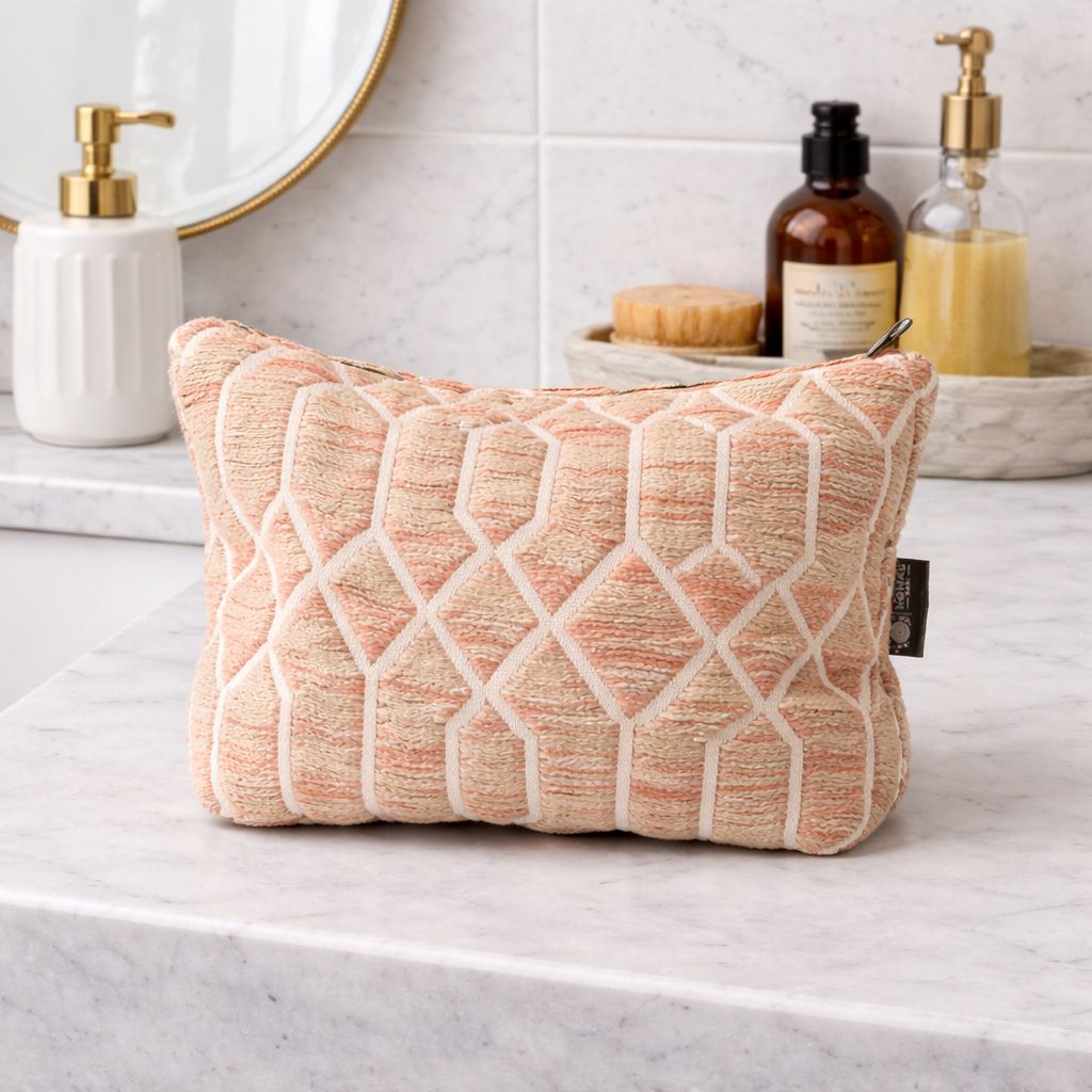 Cojín decorativo rectangular en tonos melocotón y beige, tejido texturizado con diseño geométrico.