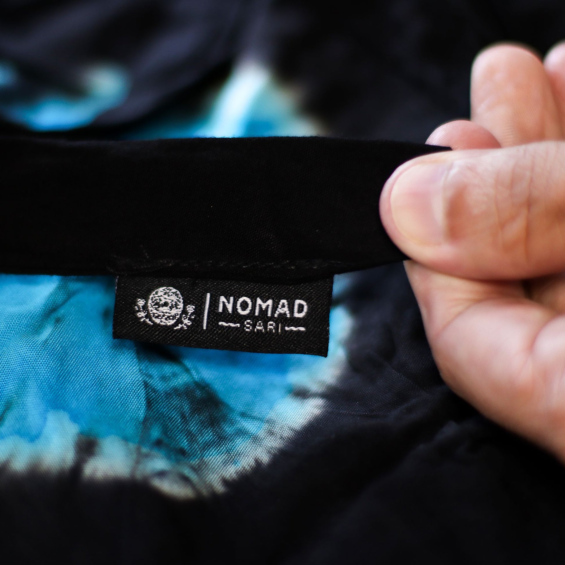 Etiqueta Nomad Sari en pantalones de descanso estilo japonés, tela suave con patrón tie-dye azul y negro.