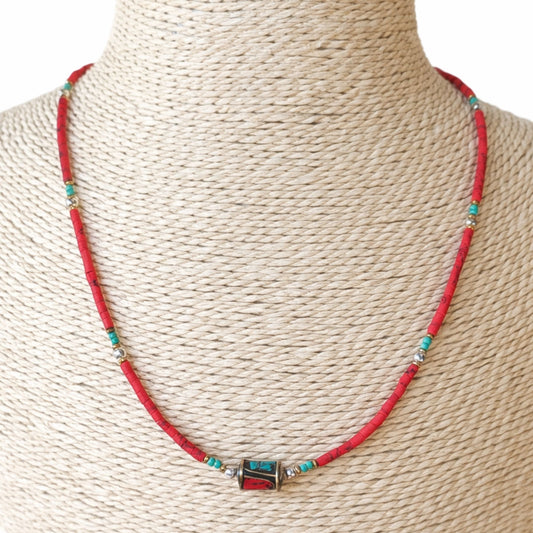 Collar artesanal rojo y turquesa de cuentas, con detalle metálico, estilo bohemio elegante.