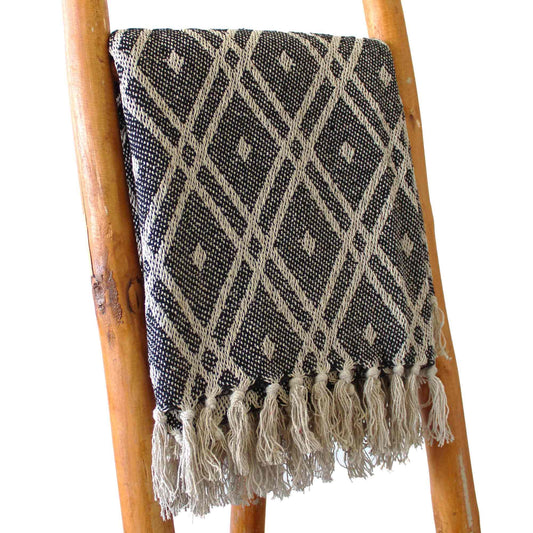 Manta decorativa de algodón negro con diseño a rombos y flecos en color natural. Ideal para abrigo y estilo bohemio.