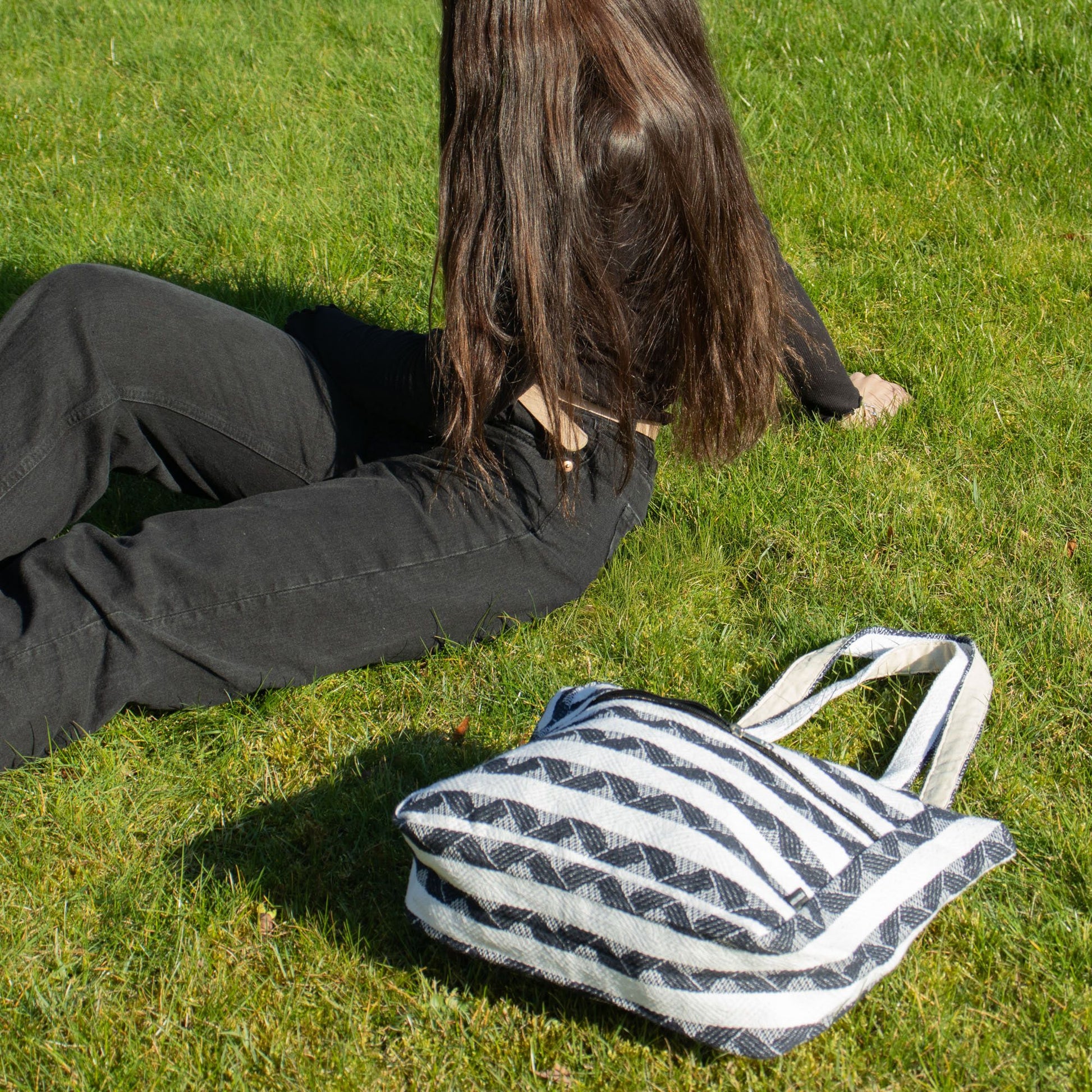 Bolso de rayas blanco y negro en tela de algodón, estilo casual, sobre césped verde.