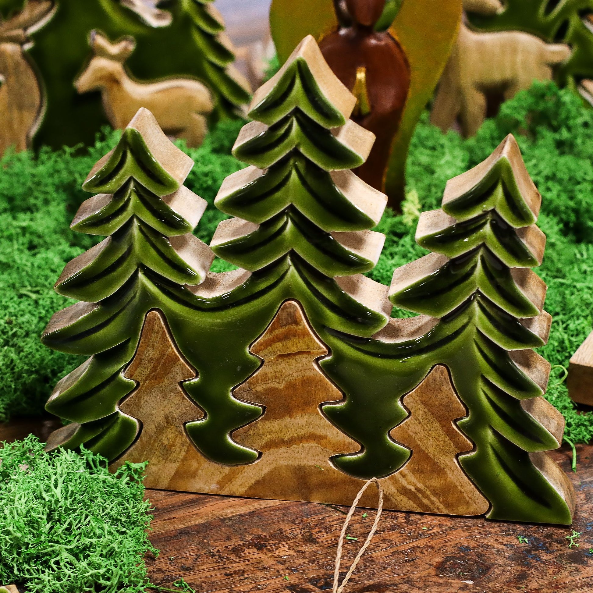 Figuras de madera en tonalidades verdes, estilo rústico, representando árboles en miniatura para decoración.
