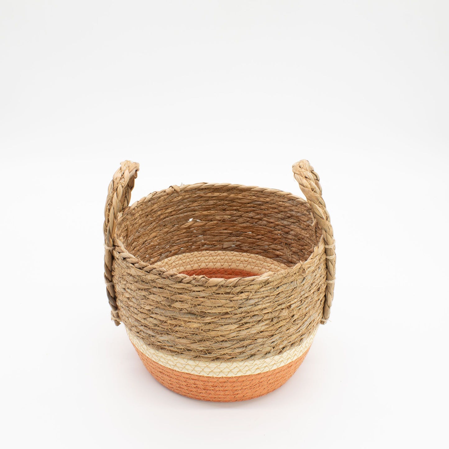 Cesta artesanal de pasto marino con base naranja y blanca, tejido natural y dos asas laterales sobre fondo blanco.