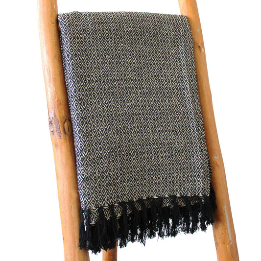 Manta de algodón negro y beige con diseño geométrico y flecos, perfecta para decoración moderna.