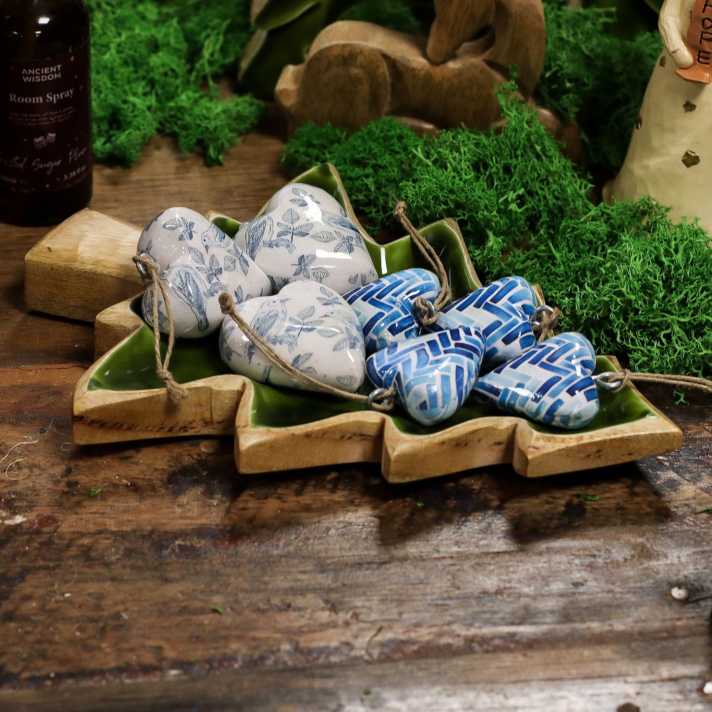 Corazones decorativos de cerámica azul y blanca en un plato verde, ideales para decoración bohemia y natural.