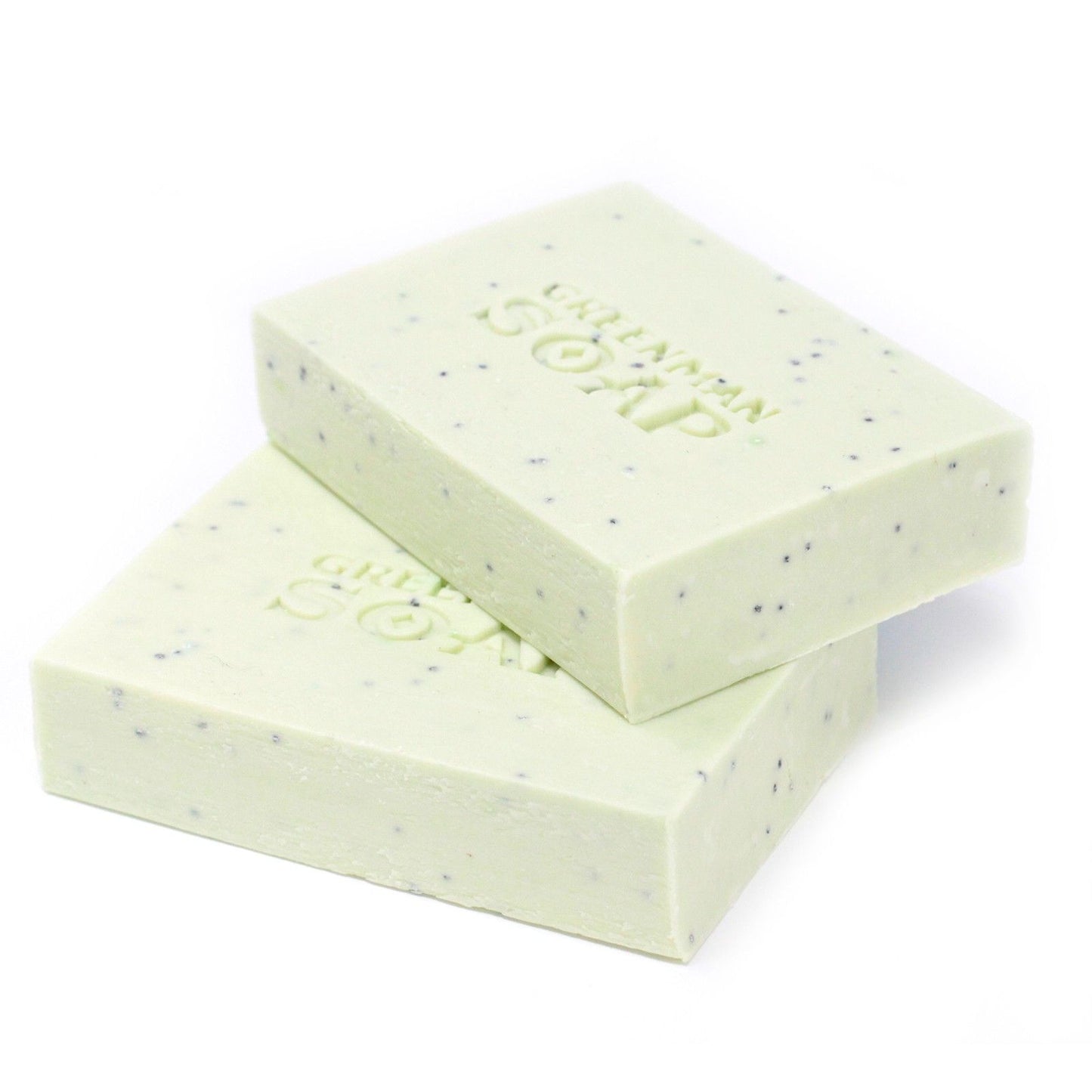 Dos jabones rectangulares de color verde claro, con motas oscuras y el sello "GREENMAN SOAP" grabado, sobre fondo blanco.