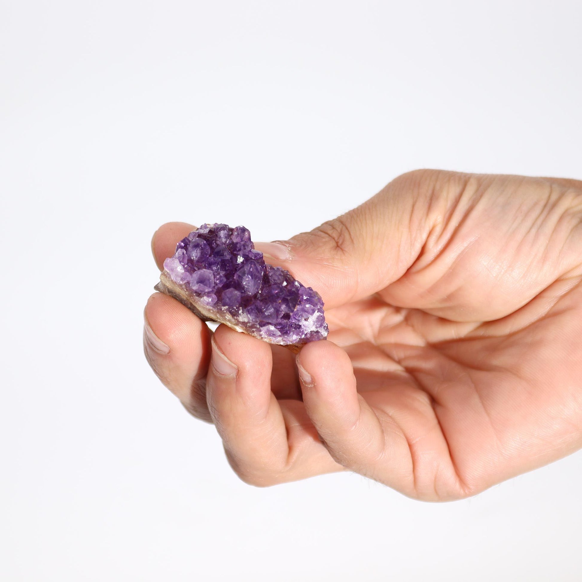 Cristal de amatista morado en mano, con brillo natural y textura rugosa, ideal para decoración y coleccionistas.