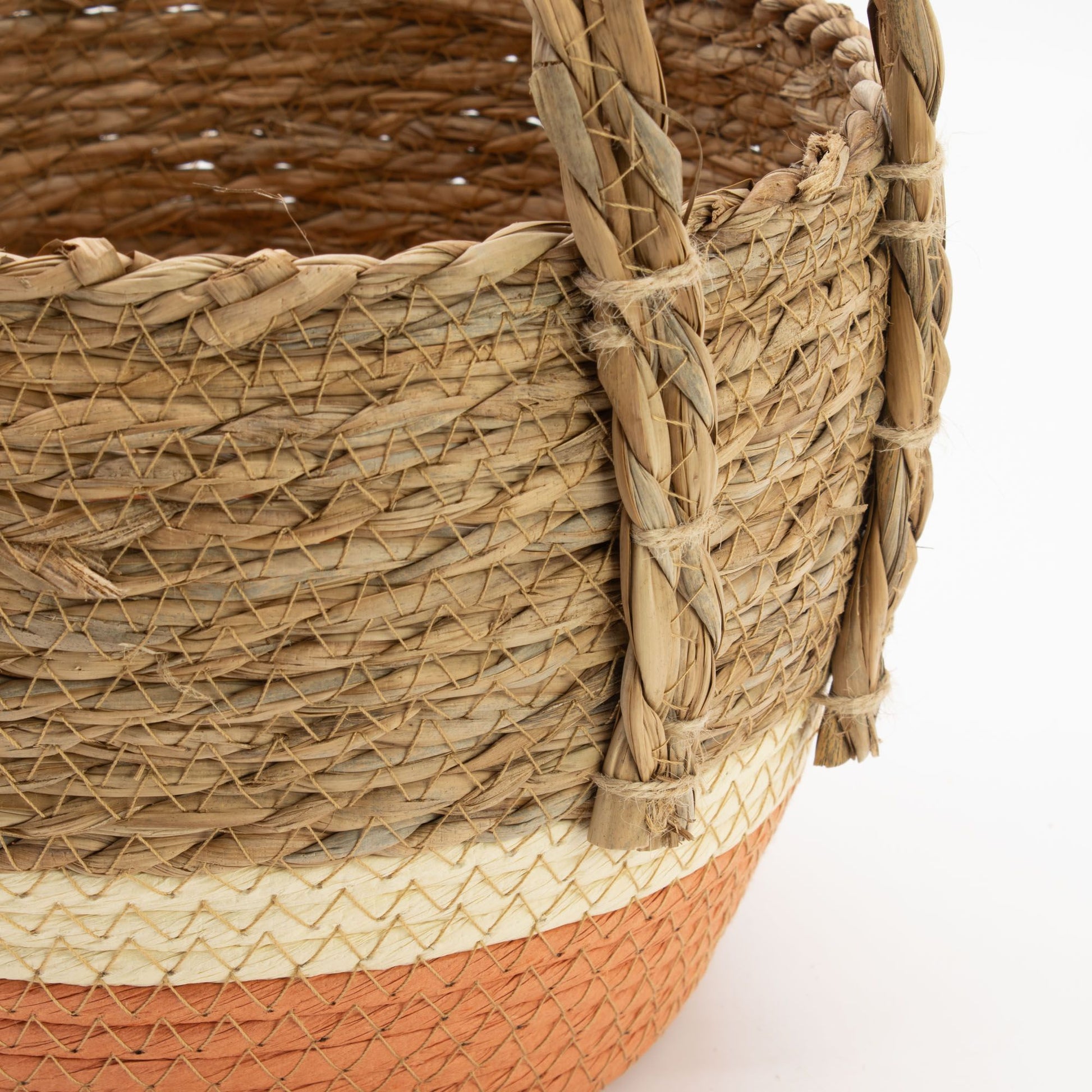 Cesta artesanal de pasto marino y hoja de plátano, con trenzado natural, base naranja y asa reforzada, estilo rústico.