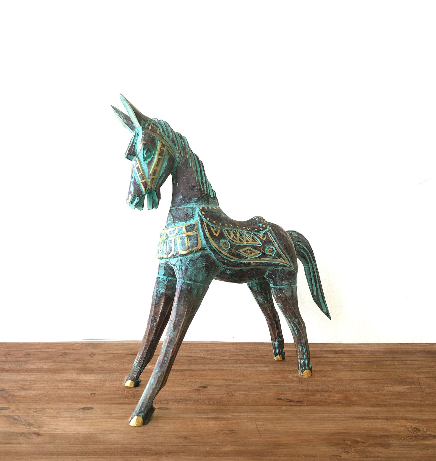 Caballo de decoración de metal verde y dorado, estilo artesanal, con detalles intrincados y base de madera.