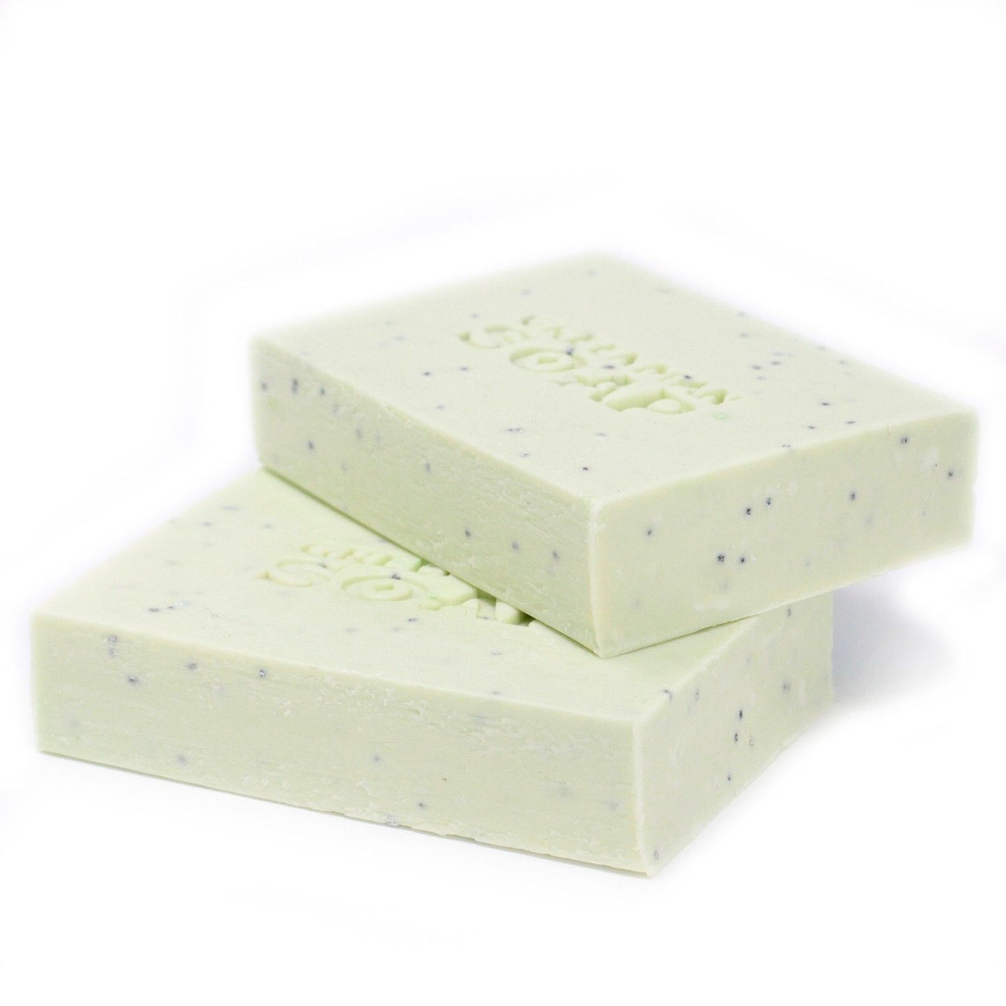Dos pastillas de jabón verde pálido, moteadas, con la palabra "SOAP" grabada, apiladas sobre un fondo blanco.
