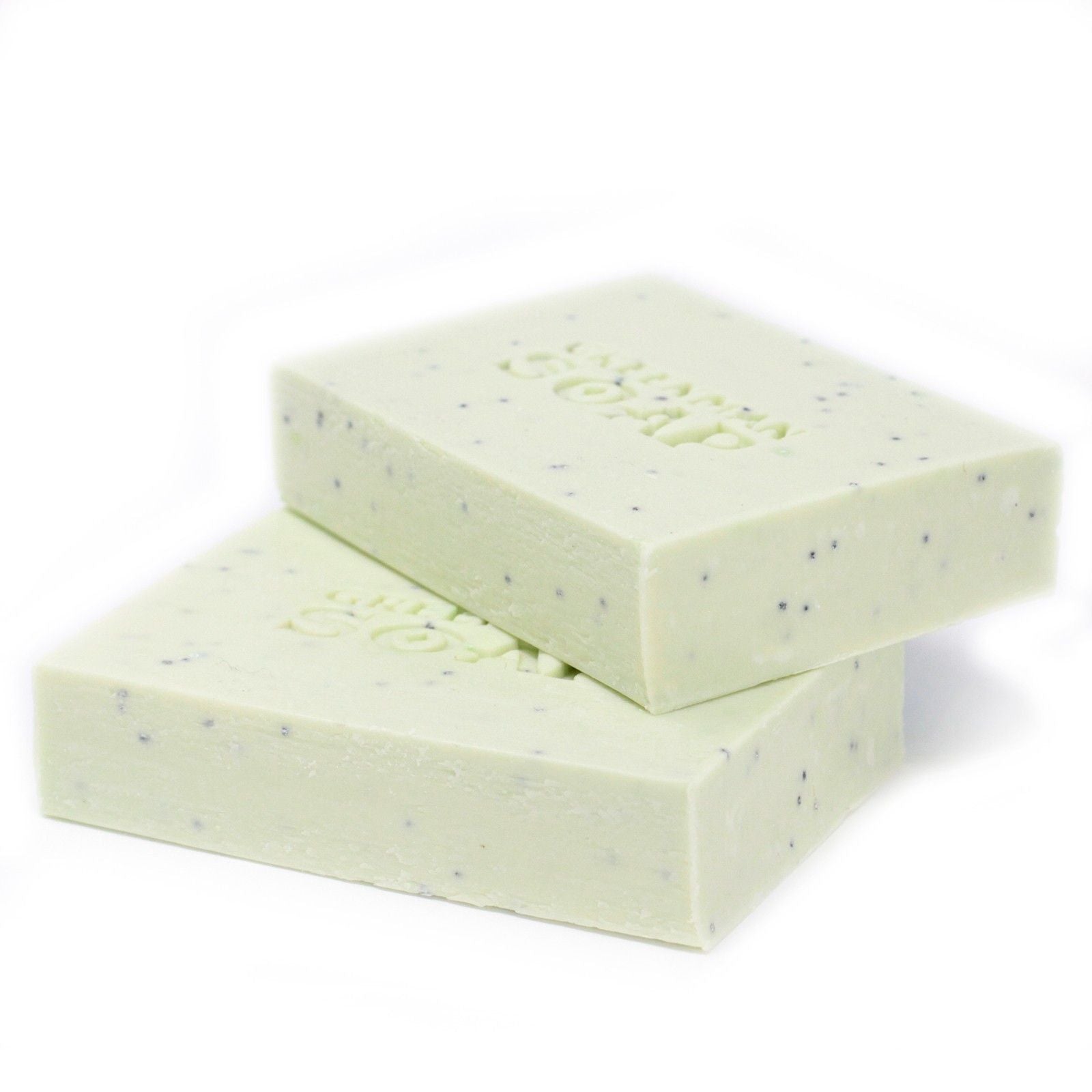 Dos pastillas de jabón verde pálido, moteadas, con la palabra "SOAP" grabada, apiladas sobre un fondo blanco.