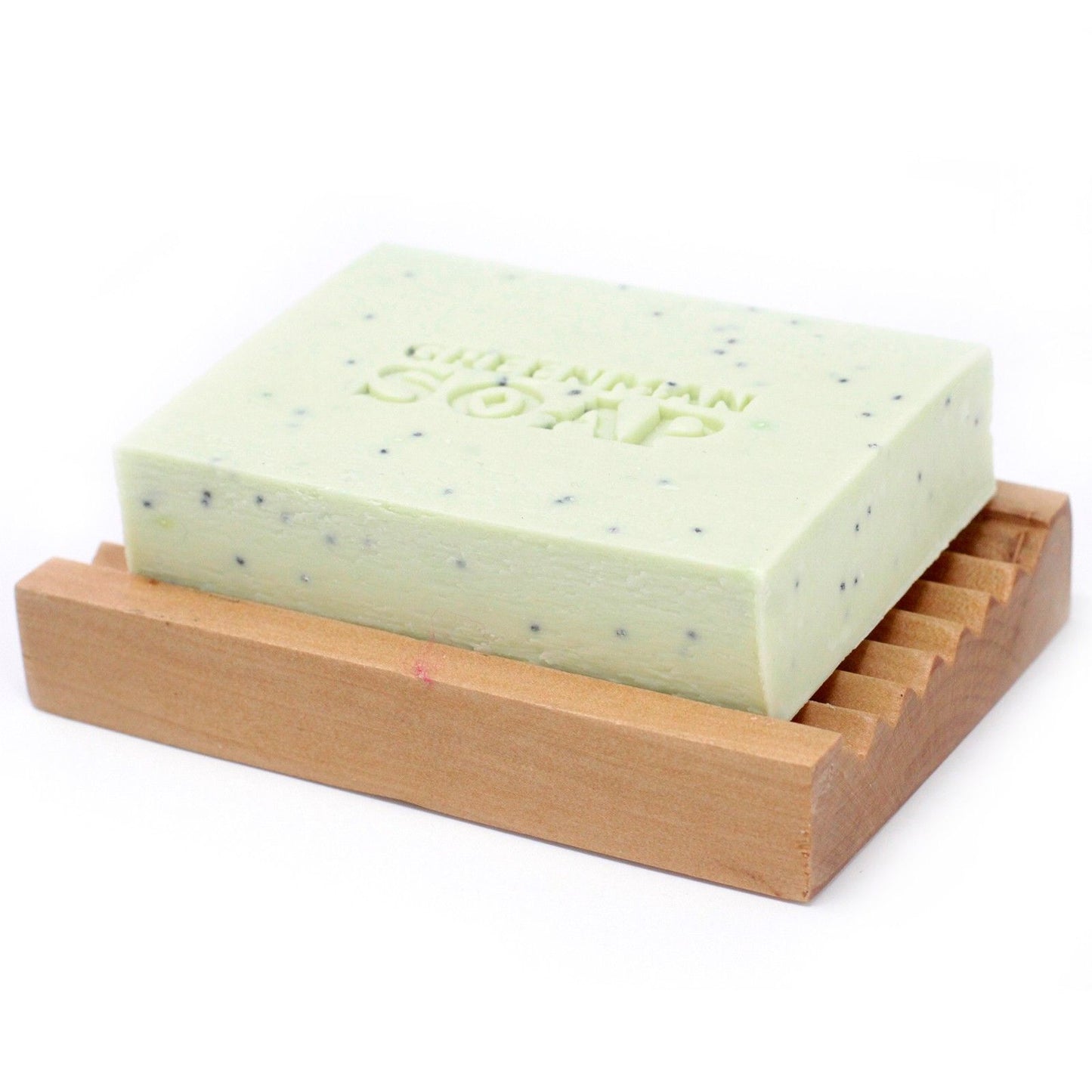 Jabón verde con puntos oscuros y grabado "GREENMAN SOAP" sobre una jabonera de madera acanalada. Fondo blanco.