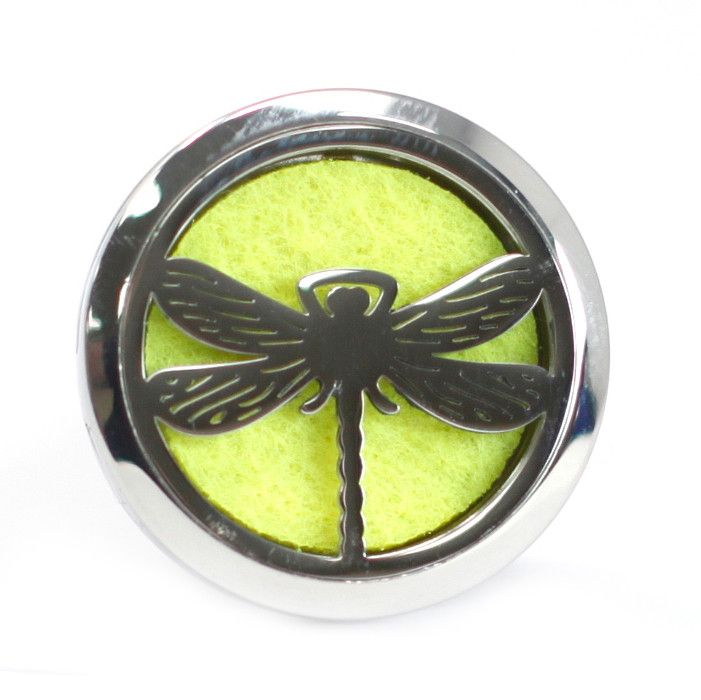 Difusor circular de coche (30mm) en metal plateado con diseño de libélula calada sobre almohadilla de fieltro amarilla.