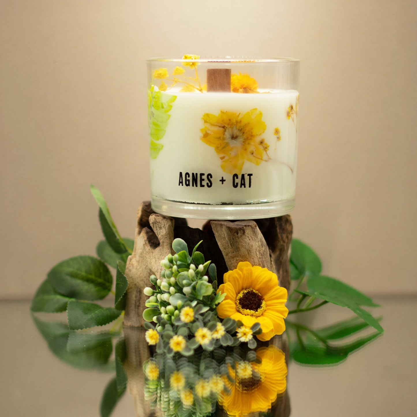 Vela aromática de cera blanca con diseño floral en vidrio, mecha de madera y base de madera natural.