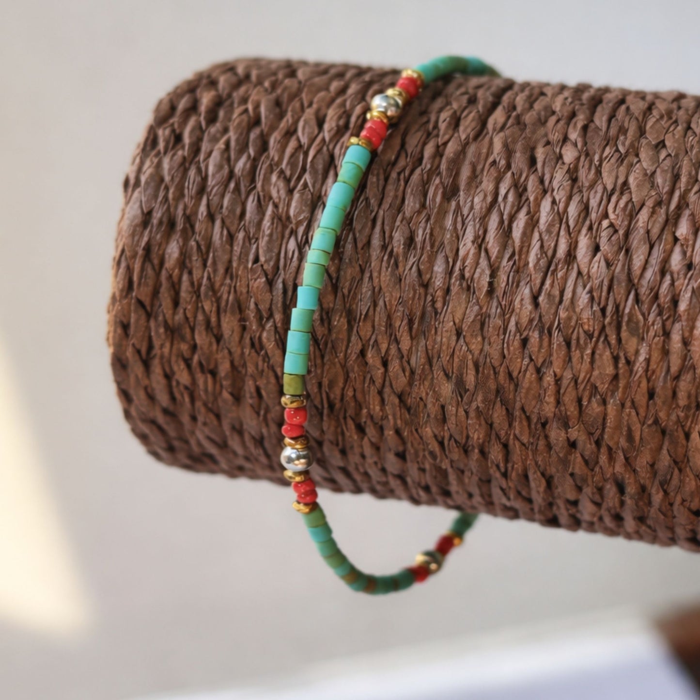 Pulsera artesanal verde, roja y dorada, hecha de cuentas de cerámica y metal, estilo bohemio.