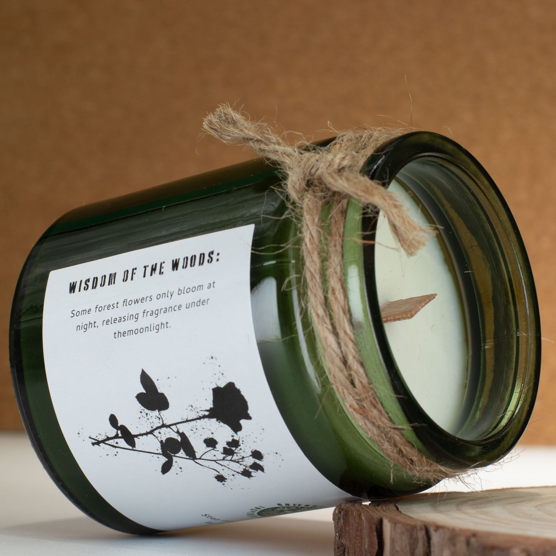 Vela aromática verde en frasco de vidrio, con cuerda de yute y etiqueta blanca, fragancia floral nocturna.