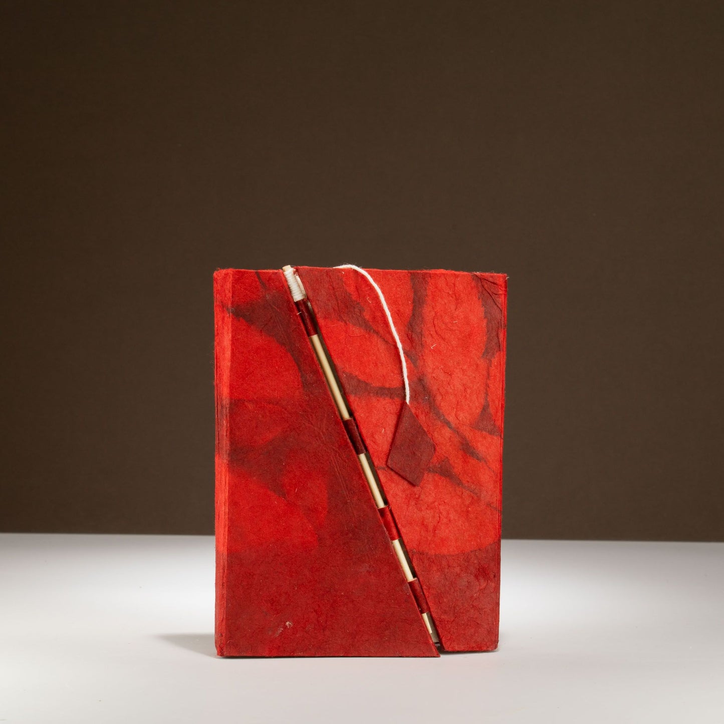 Cuaderno rojo de papel reciclado con pluma dorada, estilo artesanal y diseño de mármol. Ideal para escritura creativa.