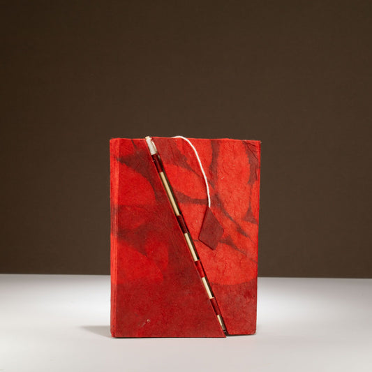 Cuaderno rojo de papel reciclado con pluma dorada, estilo artesanal y diseño de mármol. Ideal para escritura creativa.
