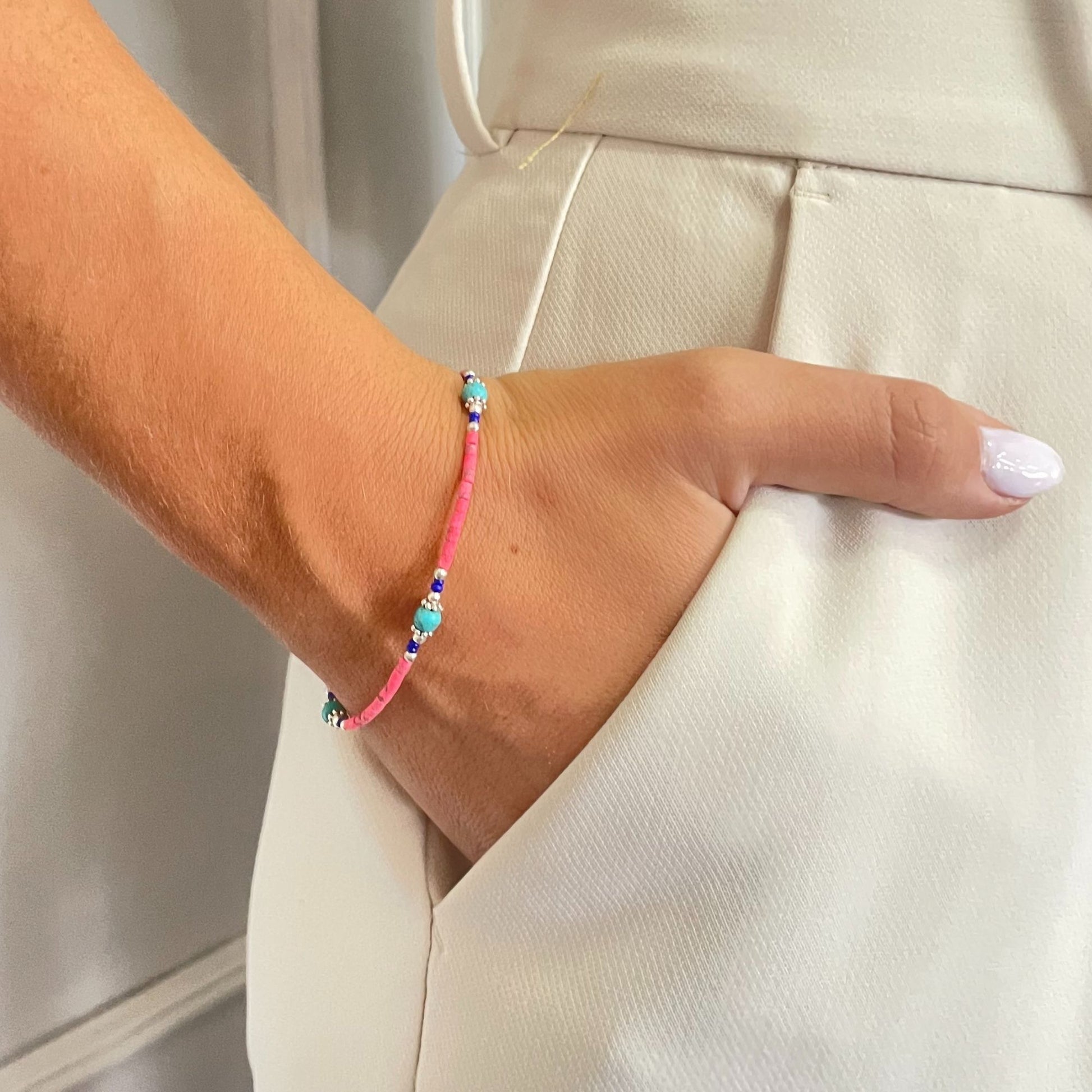 Pulsera de cuentas de colores, hilo rosa y detalles brillantes, estilo bohemio, perfecta para un look veraniego.