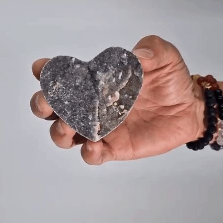 Corazón de piedra gris en mano, hecho de cristal natural, ideal para decoraciones o regalos.