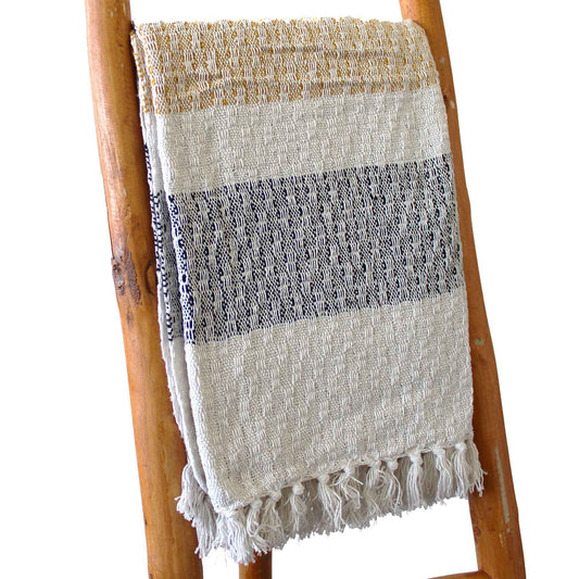 Toalla de algodón beige con franjas negras y doradas, estilo artesanal, decorativa con flecos.