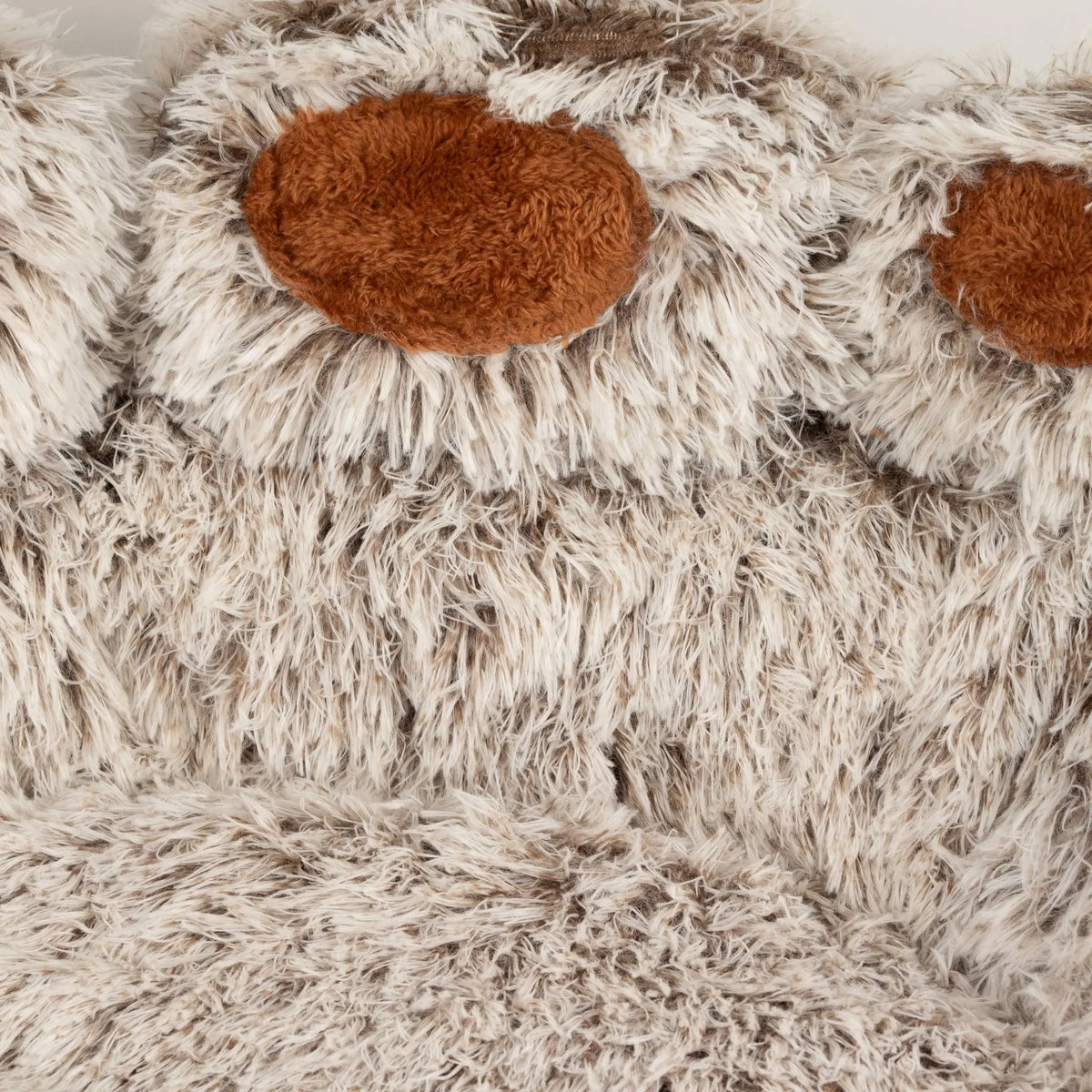 Detalle del pelo largo y las almohadillas marrones de la cama con forma de huella