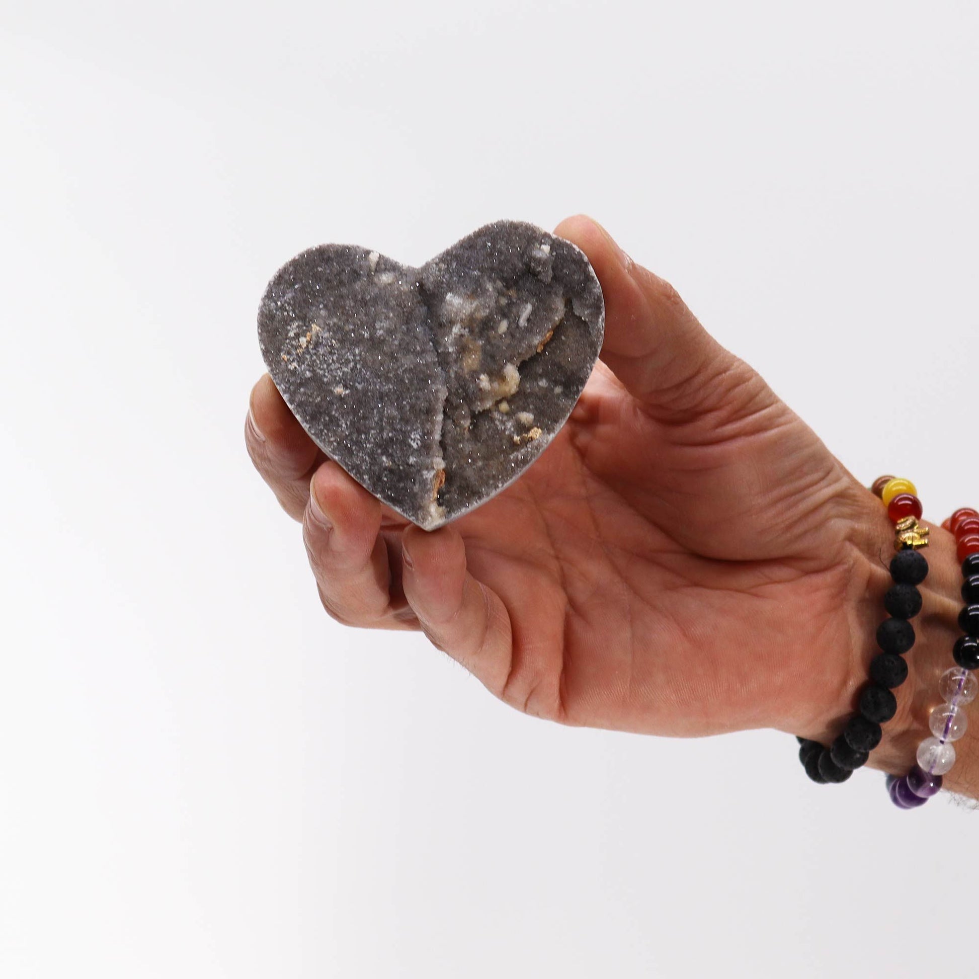 Jabón artesanal en forma de corazón, color gris oscuro con texturas naturales y detalles en blanco.