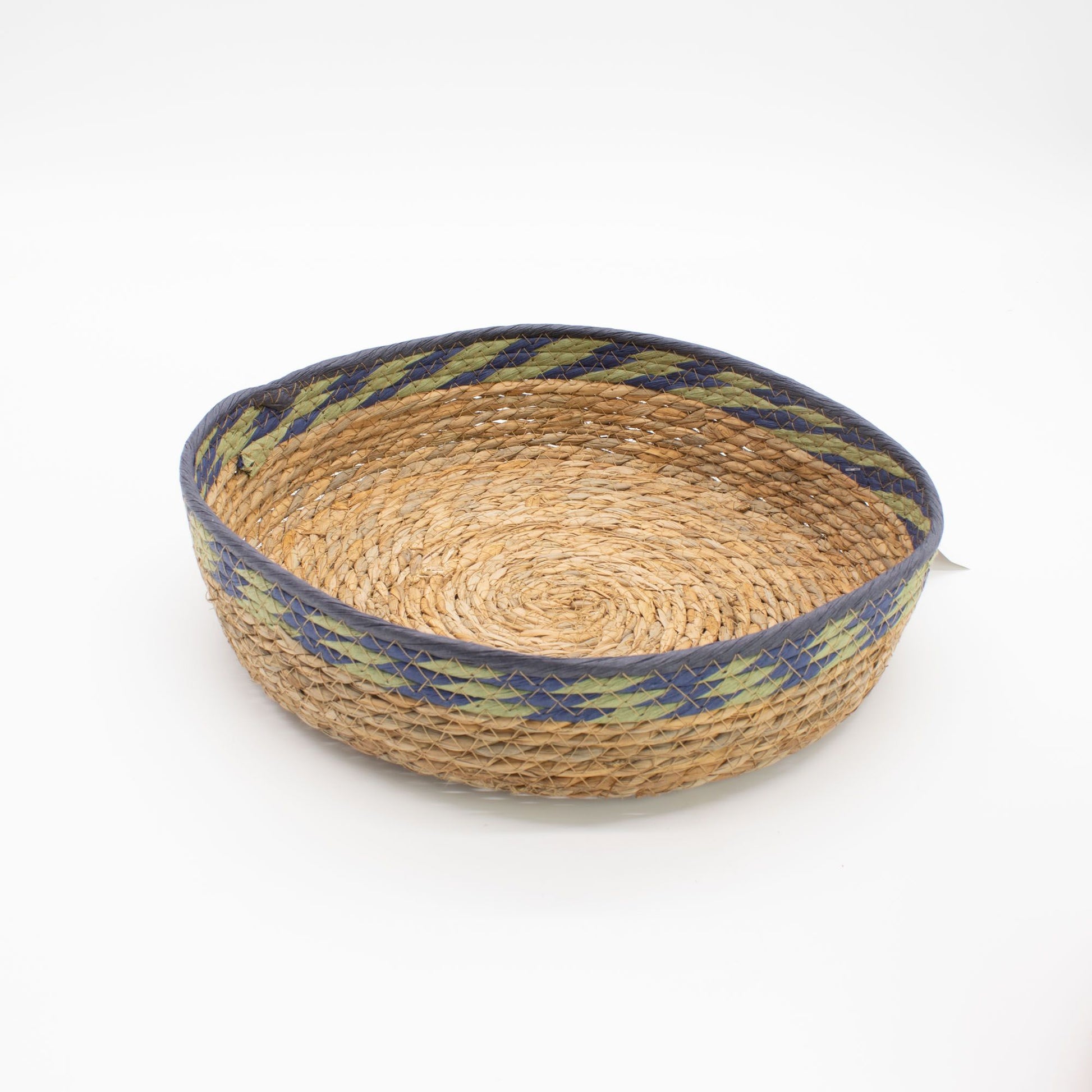 Cesta bandeja de pasto marino natural con trenzado circular y borde decorativo en azul y verde. Estilo artesanal.