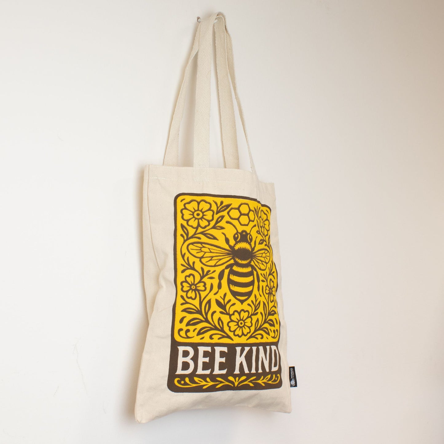 Bolsa de tela beige con diseño amarillo de abeja y frase "BEE KIND" en estilo vintage. Ideal para compras ecológicas.