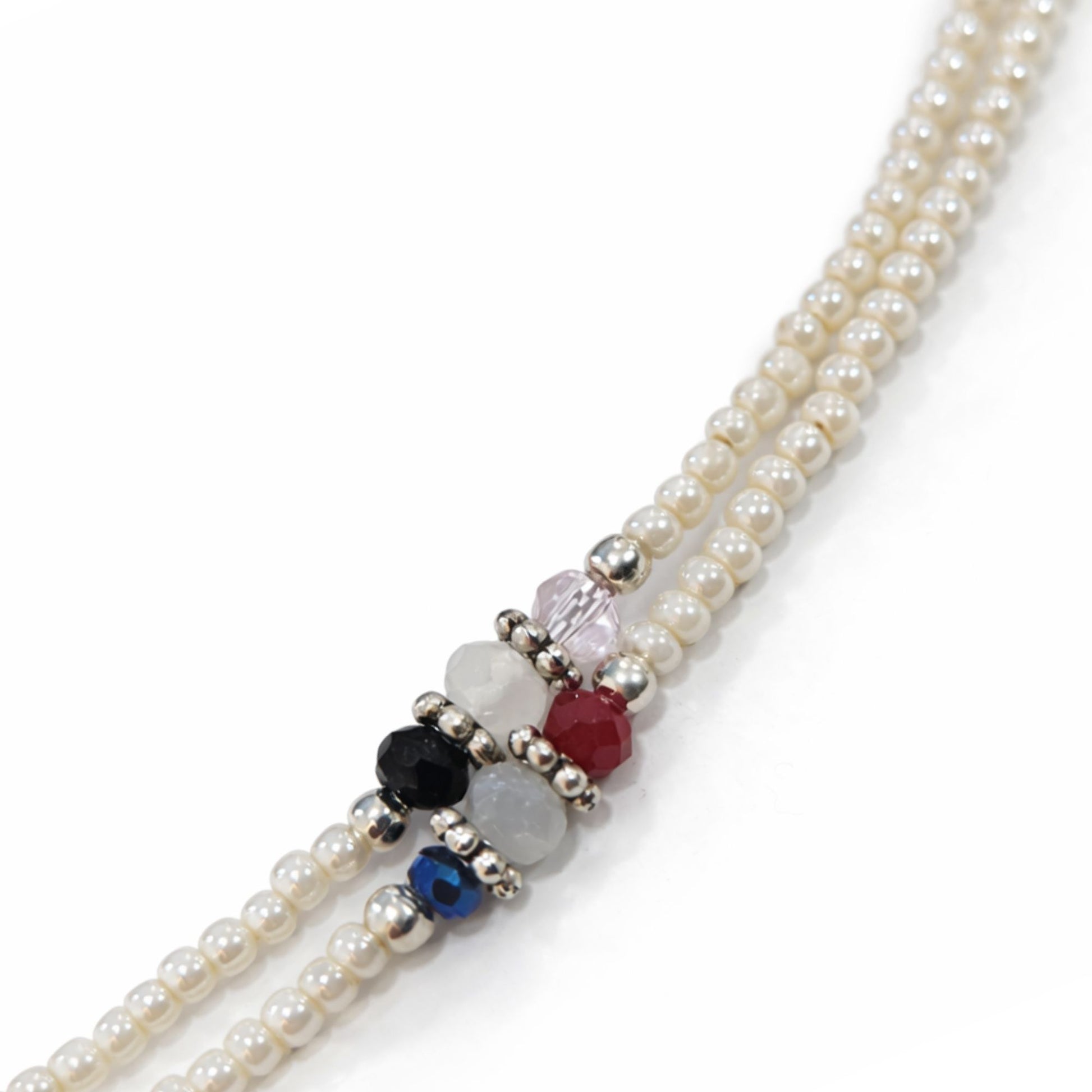 Collar de perlas blancas con cuentas de colores rojo, azul y negro, y detalles en plata. Elegante y moderno.