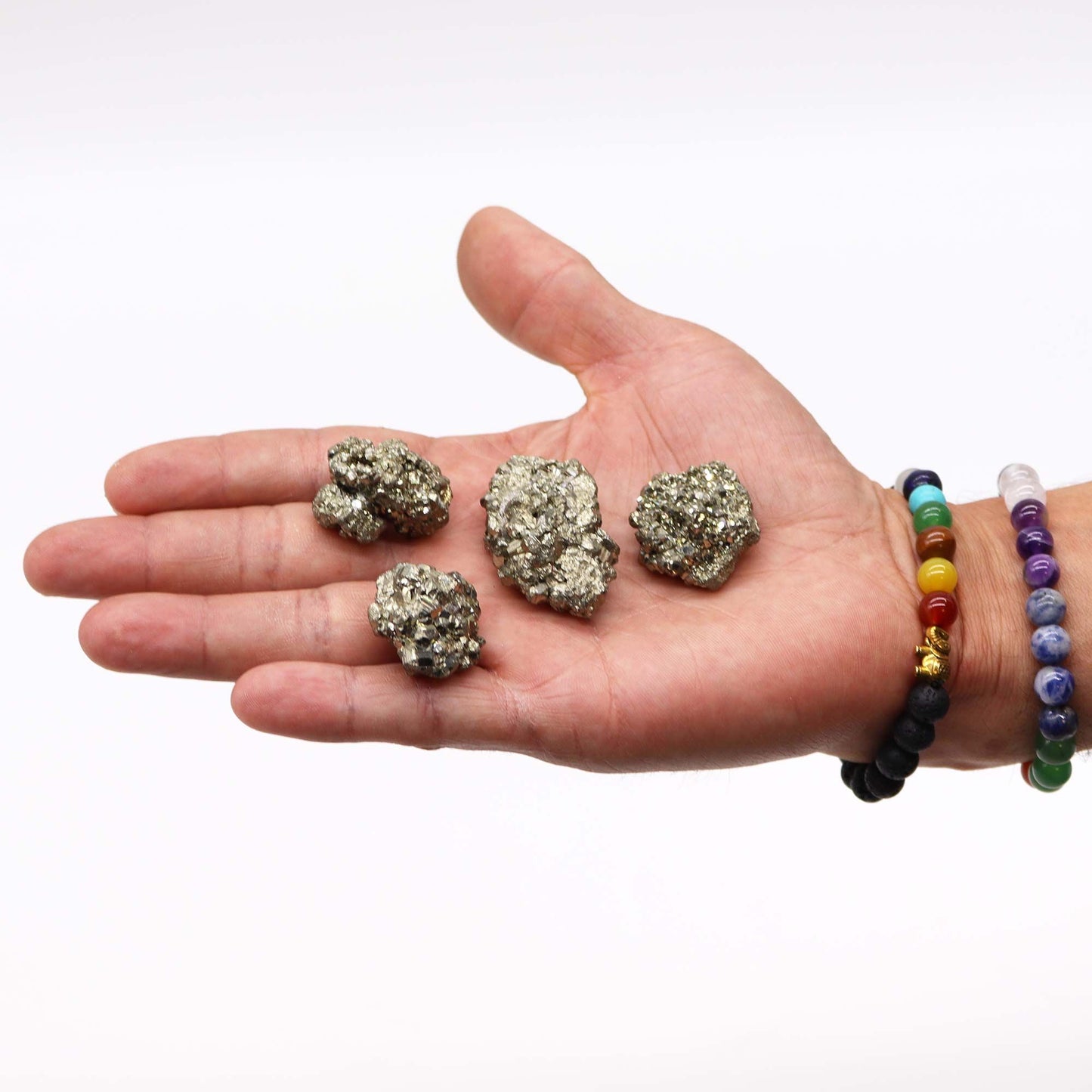 Minerales de pirita dorada en mano, brillo metálico, grabado natural, con pulsera de cuentas de colores.