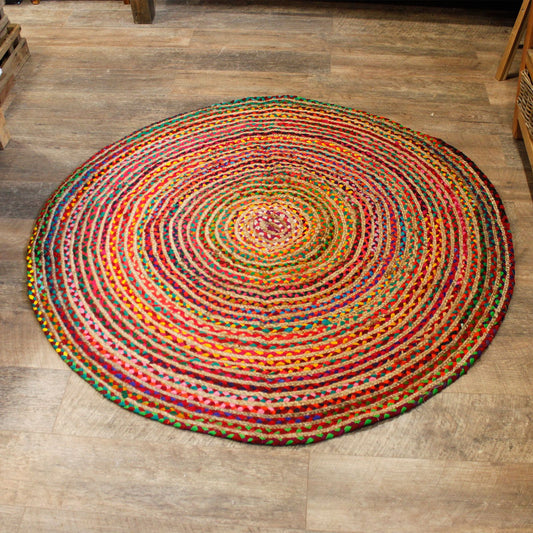 Alfombra redonda de 150 cm hecha de trenzas de yute y algodón reciclado multicolor, con diseño circular artesanal.