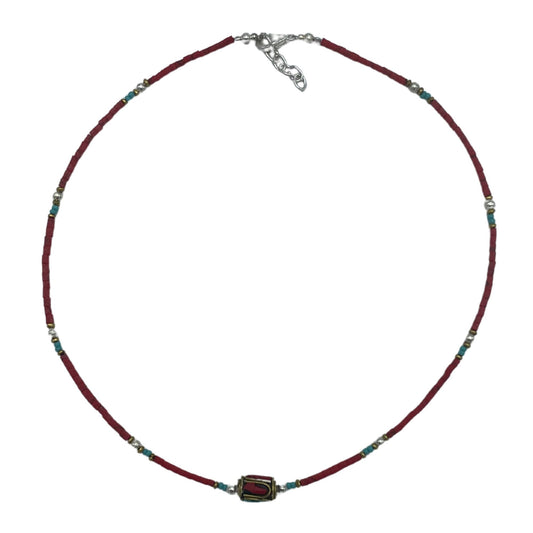 Collar de cuentas rojas y turquesas con detalles dorados y un colgante central, estilo bohemio.