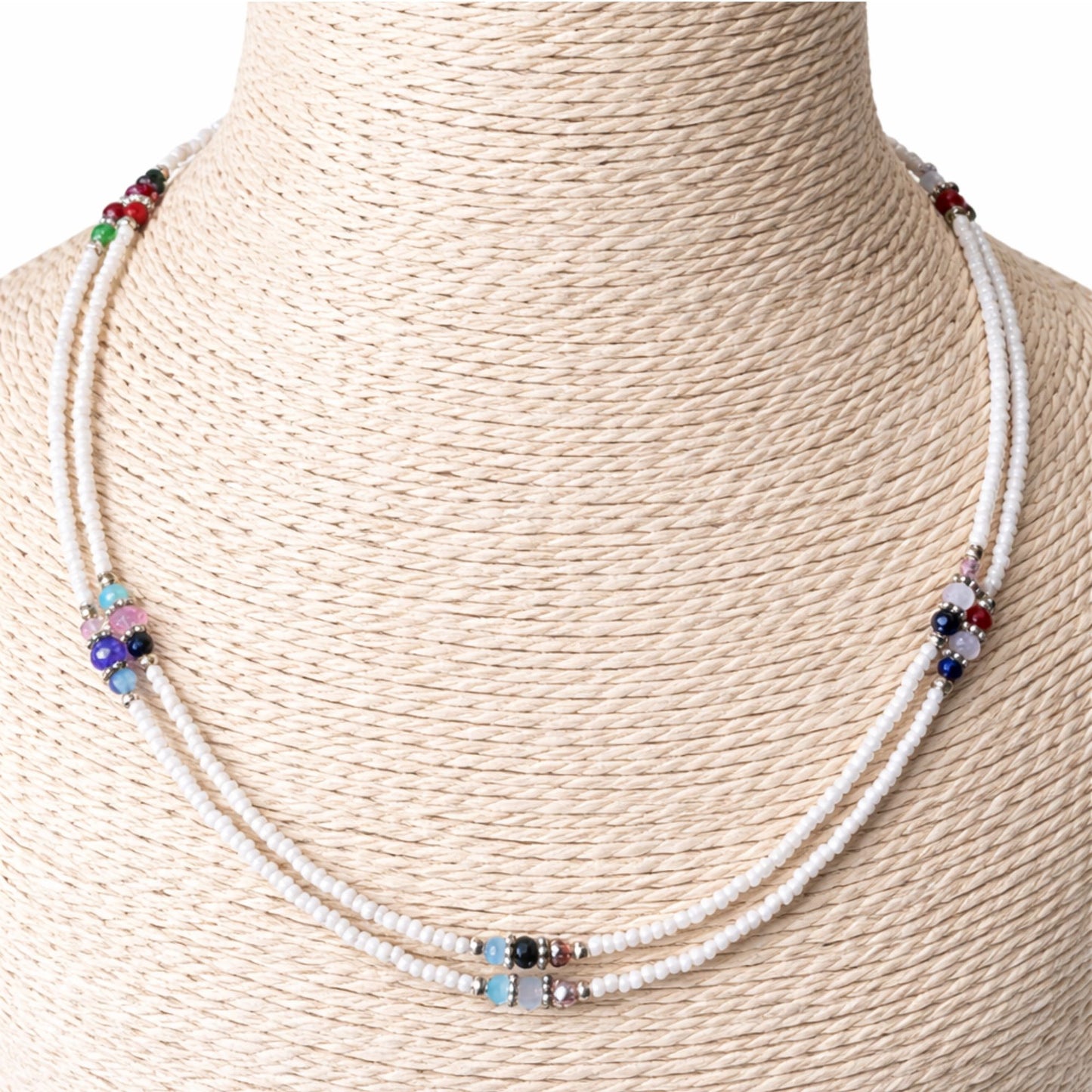 Collar de cuentas blancas y multicolores, estilo bohemio, con detalles en piedras preciosas y cierre metálico.