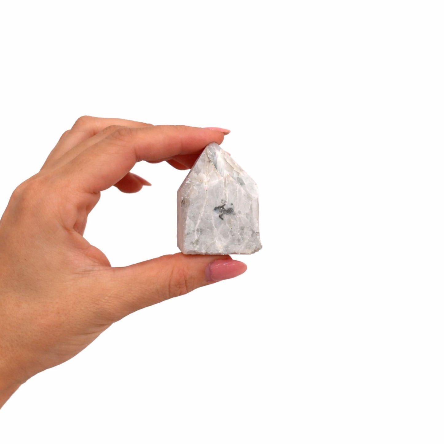 Cristal de cuarzo blanco con inclusiones grises, en forma de pirámide, sostenido por una mano.