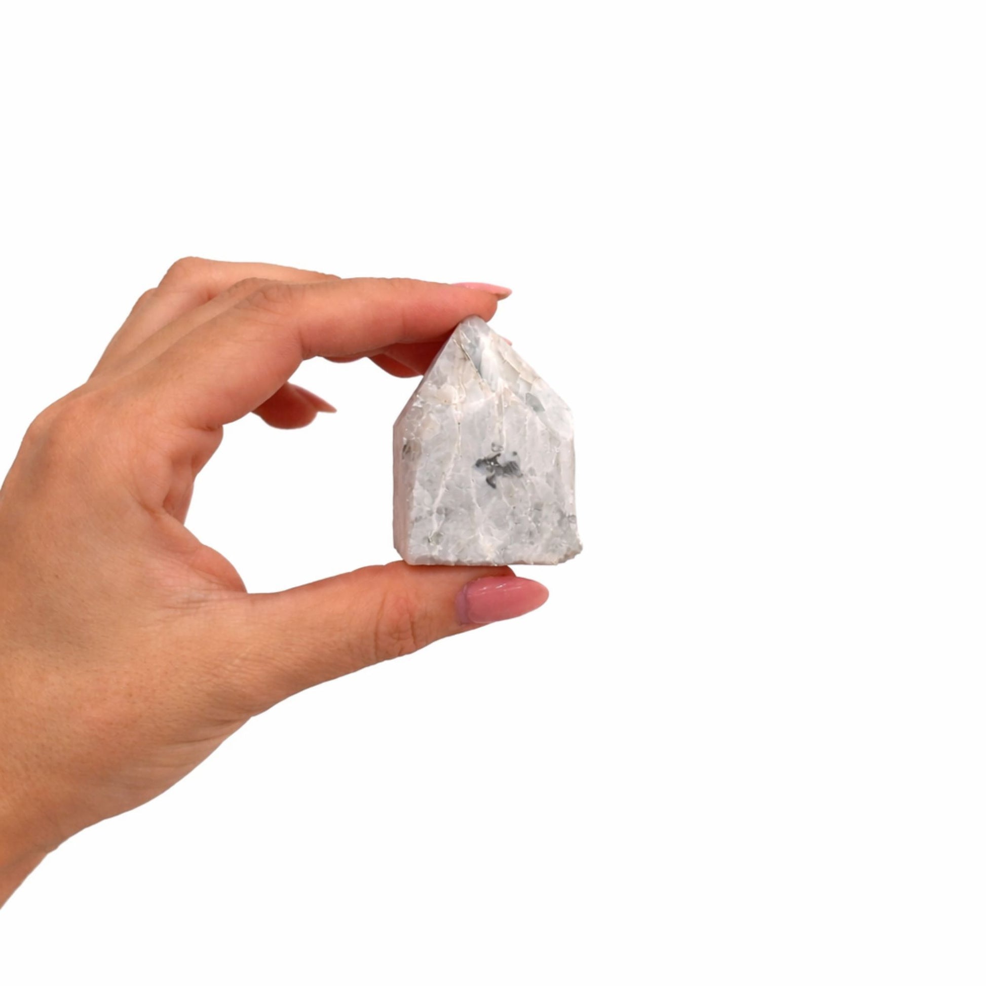 Cristal de cuarzo blanco con inclusiones grises, en forma de pirámide, sostenido por una mano.