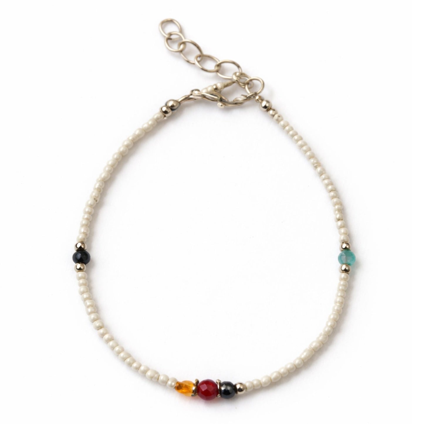 Pulsera de perlas blancas con cuentas coloridas y detalles en plata, estilo bohemio y elegante.