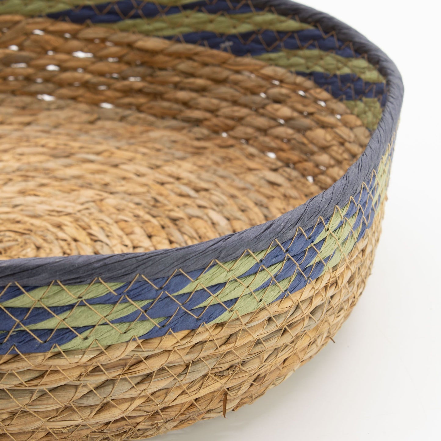 Cesta-bandeja artesanal de pasto marino y hoja de plátano, con bandas decorativas tejidas en azul y verde.