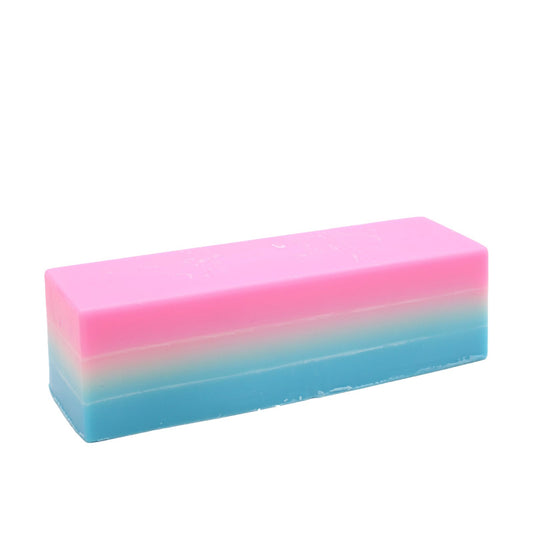 Barra de jabón artesanal rectangular con degradado de color rosa, blanco y azul sobre fondo blanco.