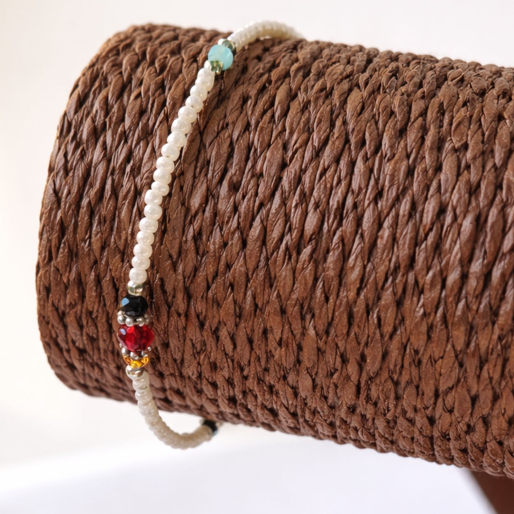 Pulsera de perlas blancas con detalles en azul, rojo y negro, estilo bohemio. Perfecta para un look elegante y colorido.