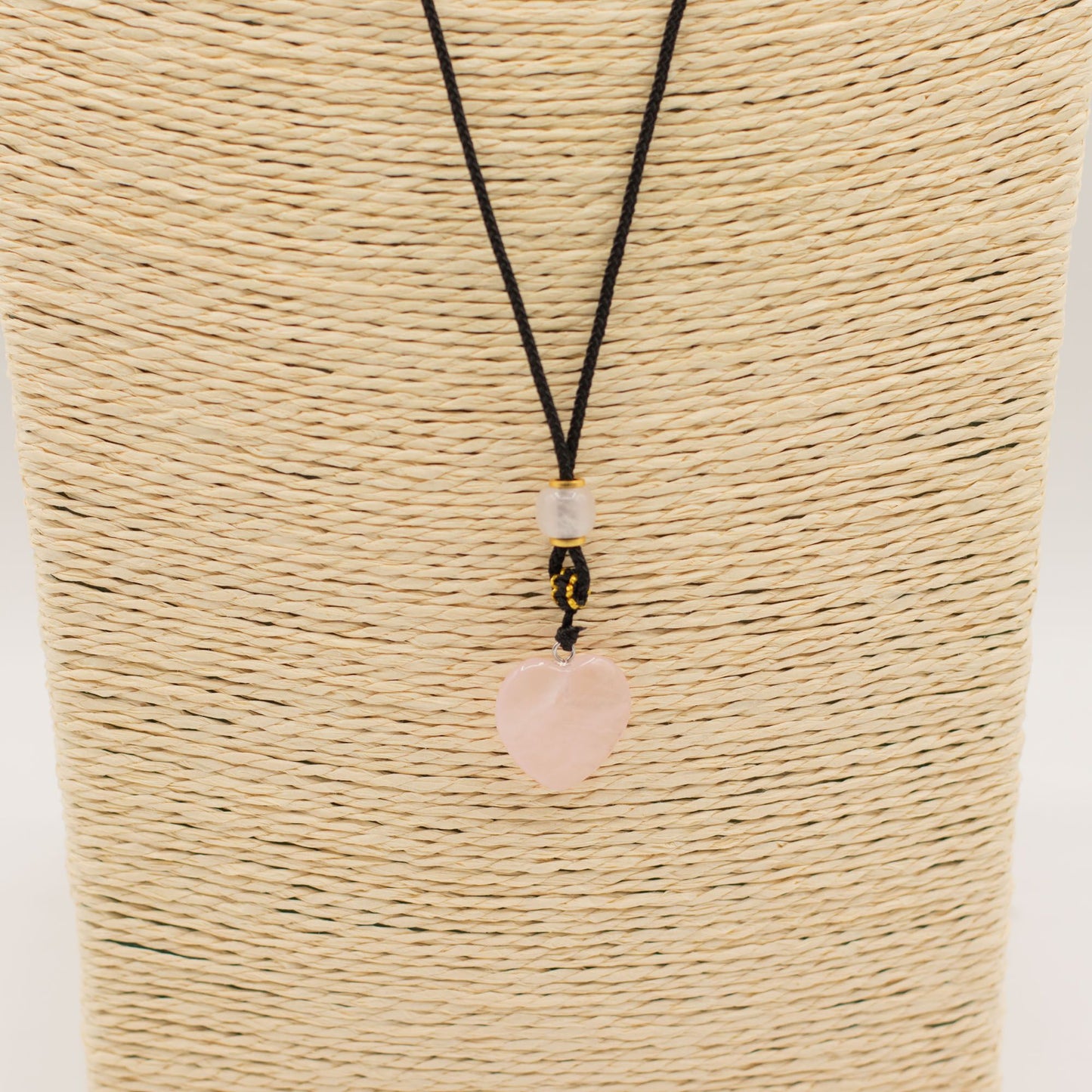 Collar de cordón negro con colgante en forma de corazón de cuarzo rosa y detalles en cuentas amarillas y transparentes.