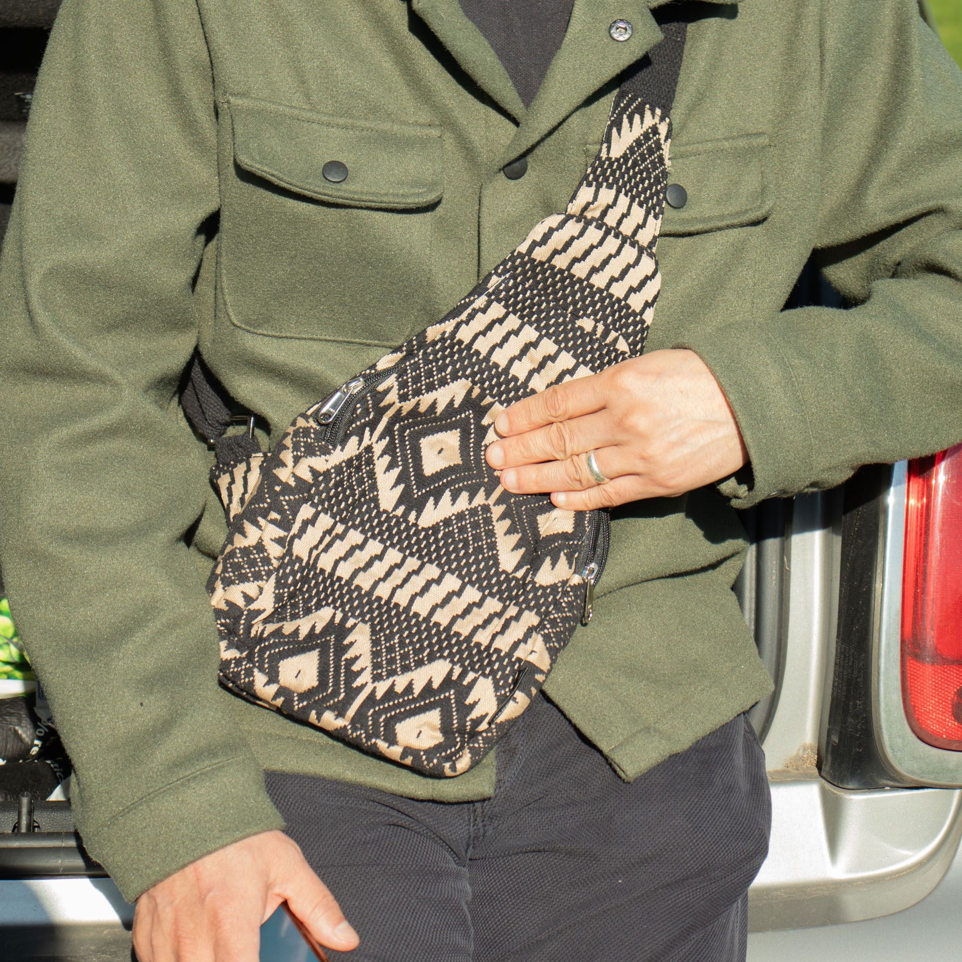 Bolso bandolera tejido en negro y beige con estampado geométrico, estilo bohemio y materiales resistentes.