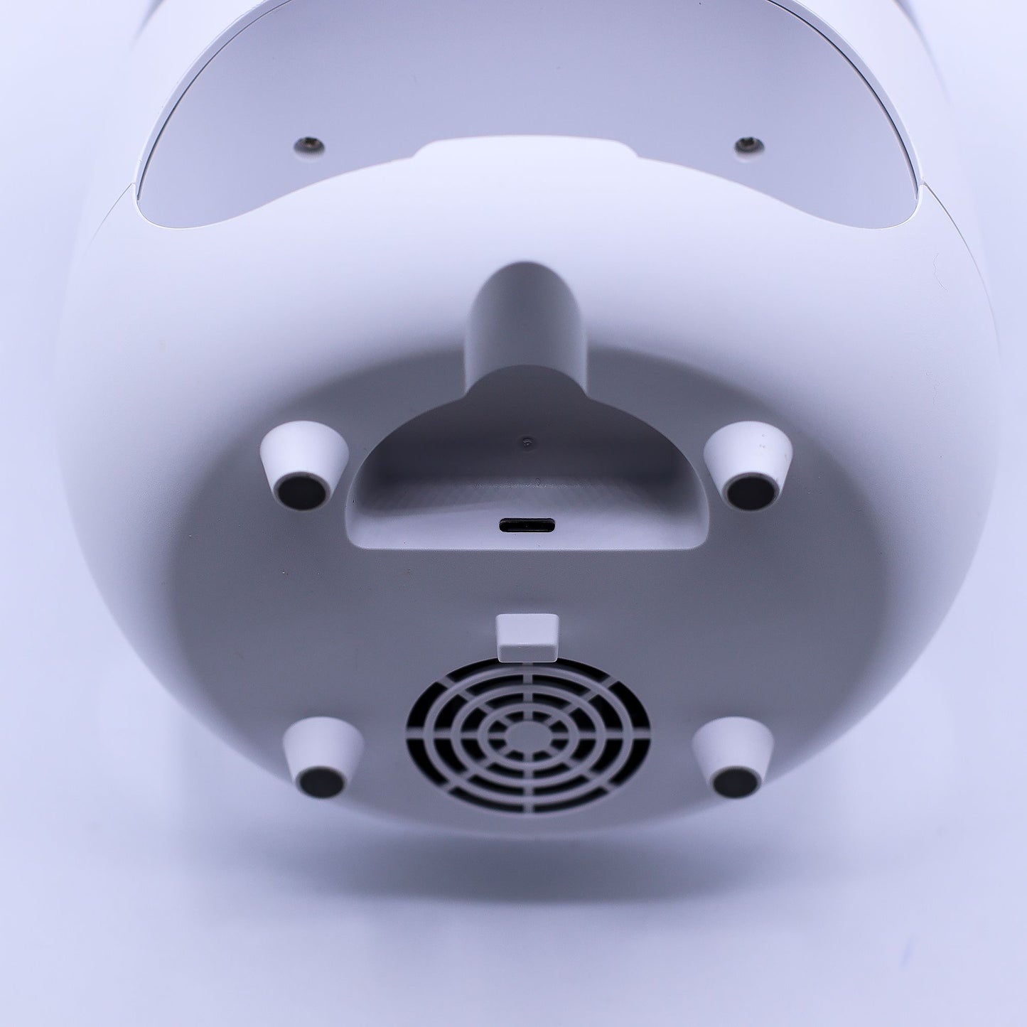 Base blanca de difusor con puerto USB-C, cuatro patas antideslizantes y rejilla de ventilación circular.